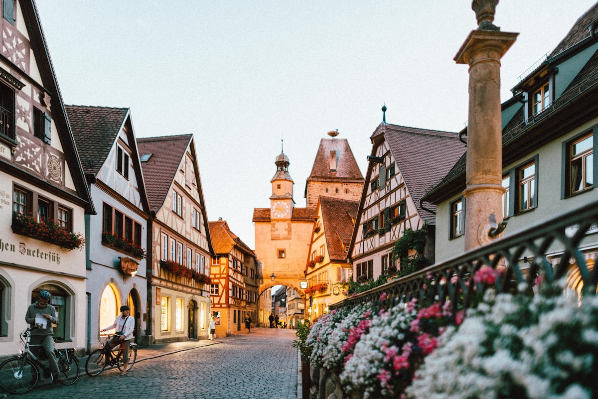 Traditional European old town square at golden hour sunset, historic cobblestone streets with glowing warm street lamps, ornate baroque architecture facades, peaceful empty atmosphere, professional travel photography